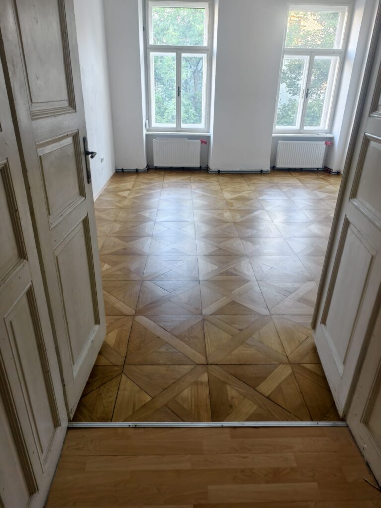 Sanierter Altbau-Hauptraum mit gleichmäßig geschliffenem Tafelparkett und seidenmatter Versiegelung