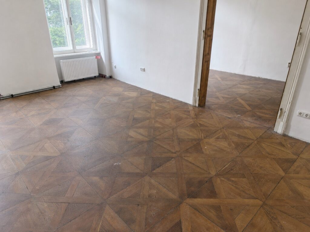Altes, stumpfes Tafelparkett vor der Sanierung in einer Altbauwohnung in Graz