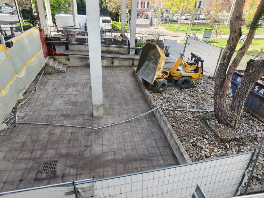 Alte Terrasse beim Cafe Kork an der TU Graz vor der Sanierung, alter Plattenbelag mit Dumper und Abbruchcontainer