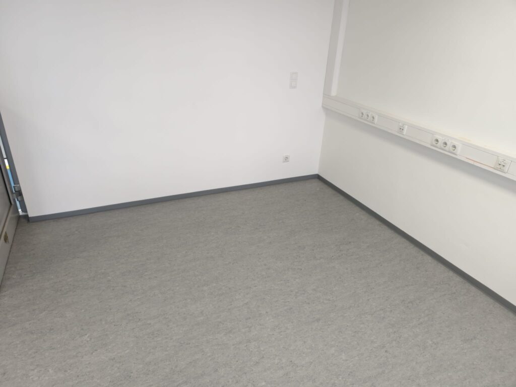 Detailansicht des sauberen Randabschlusses mit PVC-Leiste entlang der Wand, Linoleumverlegung MAGNA Ilz