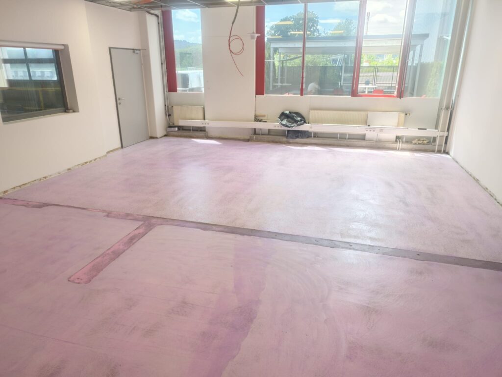 Angeschliffener und grundierter Untergrund vor der Nivellierung, Blick über die gesamte Fläche im Betriebsgebäude MAGNA Ilz