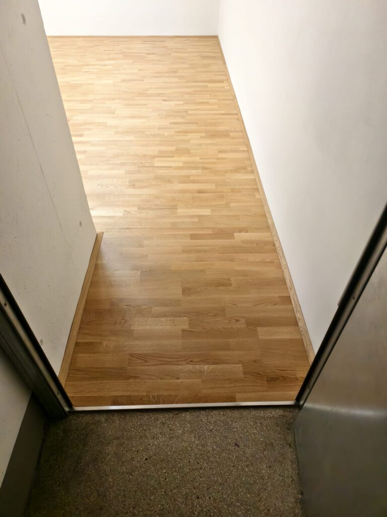 Parkettfläche im Durchgangsbereich mit massiver Holzsockelleiste und Übergangsprofil zum Bestandsboden